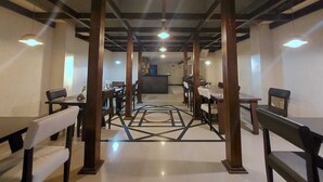 A spacious dining area with high ceilings and modern lighting fixtures. - Orbit Hotel Bagdogra (Siliguri)