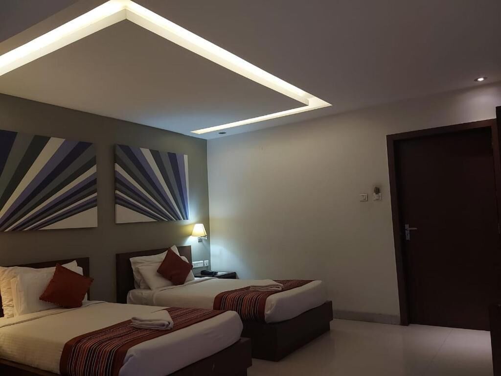 Una habitación de hotel con dos camas, una lámpara en el techo y una puerta.