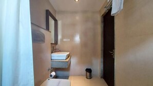 A small, compact bathroom with a single sink, a mirror, and a toilet. - Orbit Hotel Bagdogra (Siliguri)