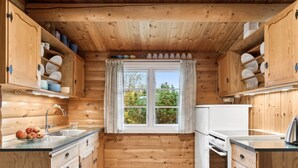 Eine Küchenzeile im Holzblockhaus-Stil mit Fenster, Holdekor-Schränken und Spüle.