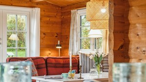Ein gemütliches Blockhaus-Interieur mit Holzausstattung, einer Couch, einem Tisch mit Lampe und einem Fenster mit Vorhängen.