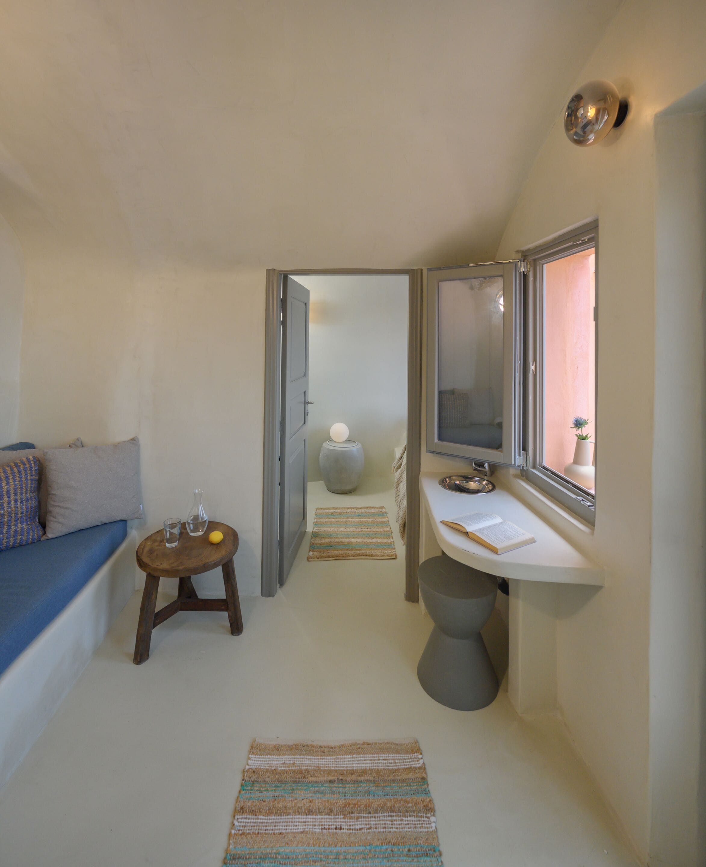 A compact room with a sofa, a small round table, a sink, and a mirror.