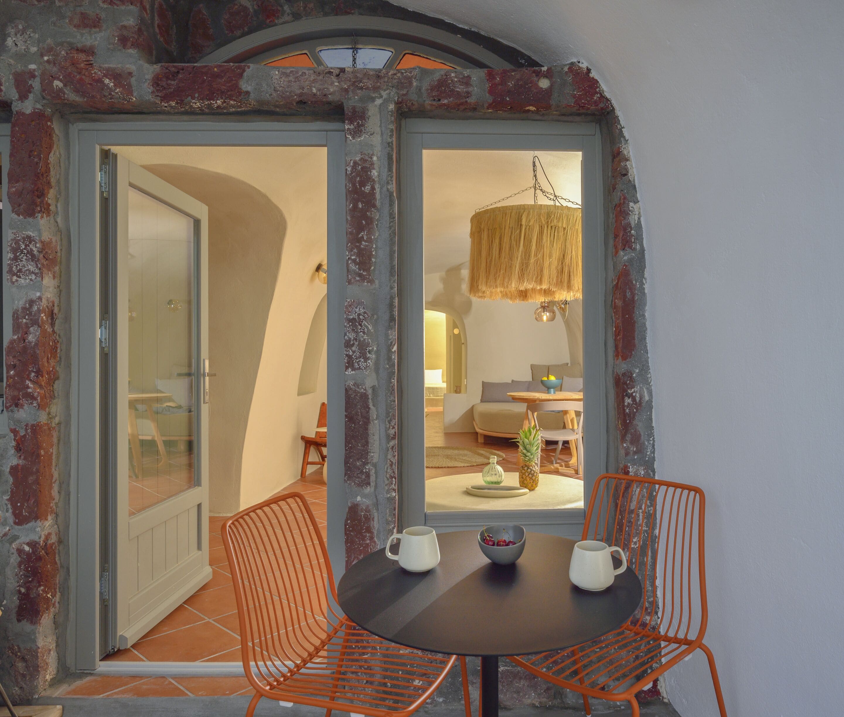 A dining area with a table, two chairs, and a hanging light fixture.