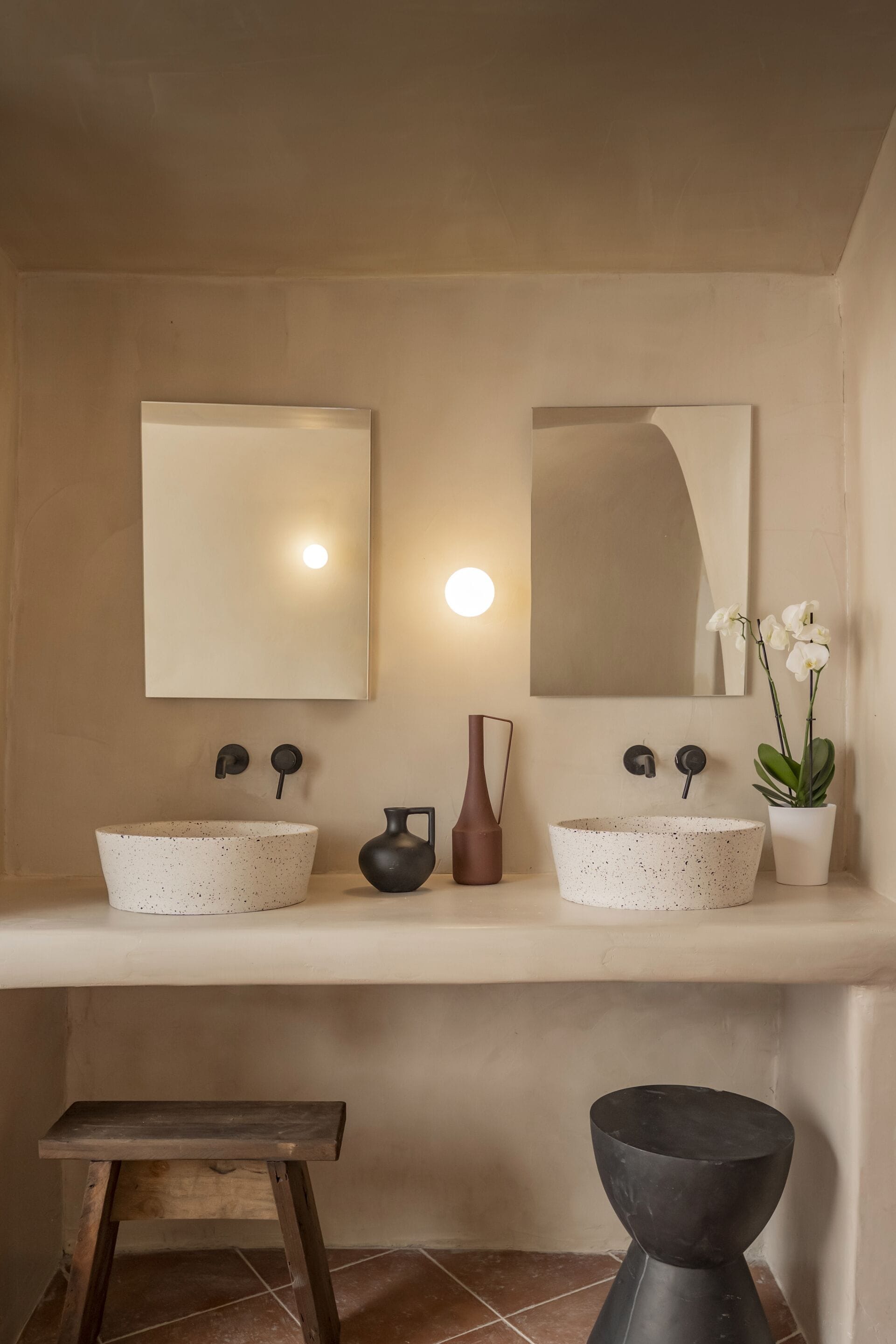 A bathroom with two sinks, a mirror, and a potted orchid.