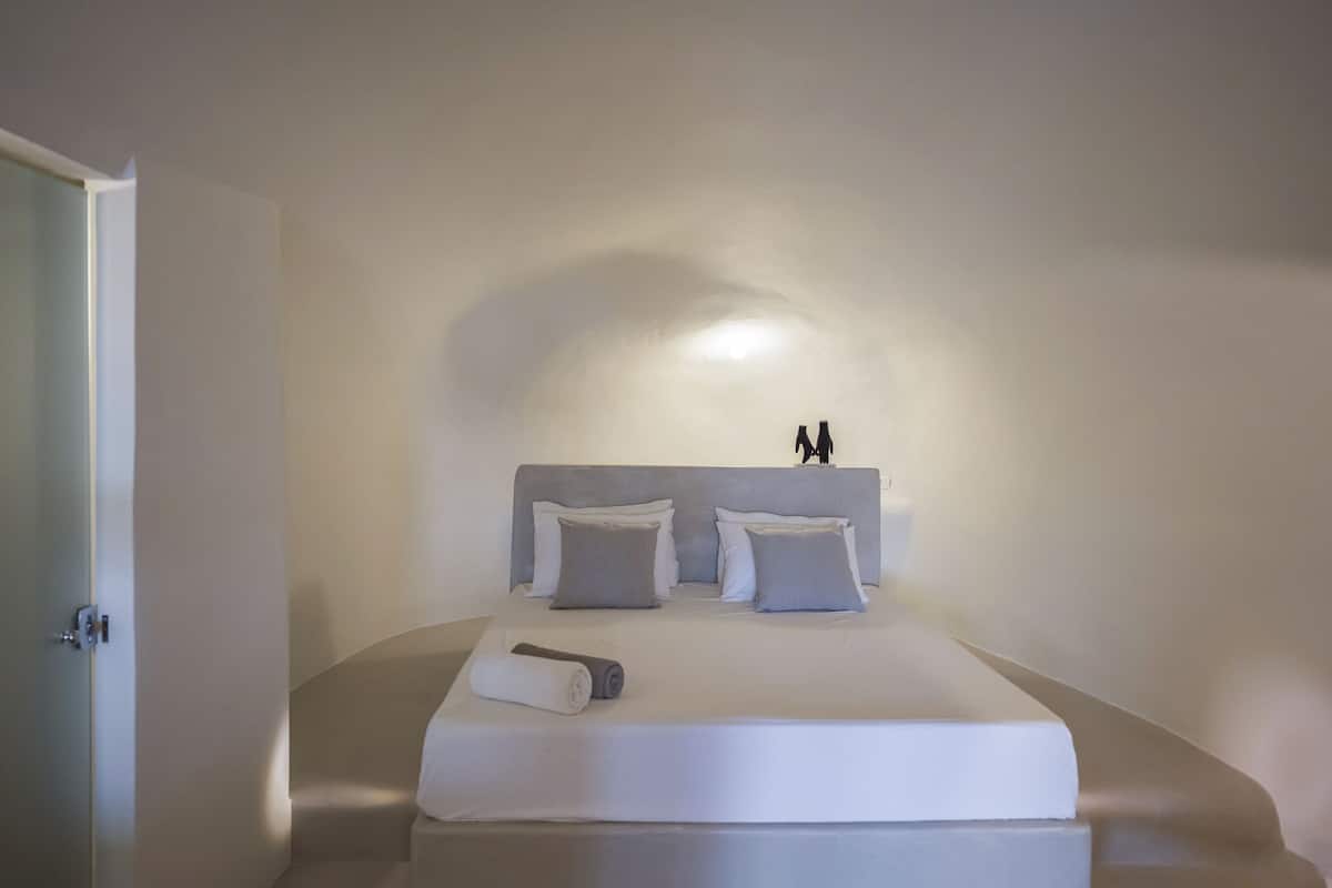 Une chambre à coucher avec un lit, des oreillers, une serviette enroulée et une table de chevet.