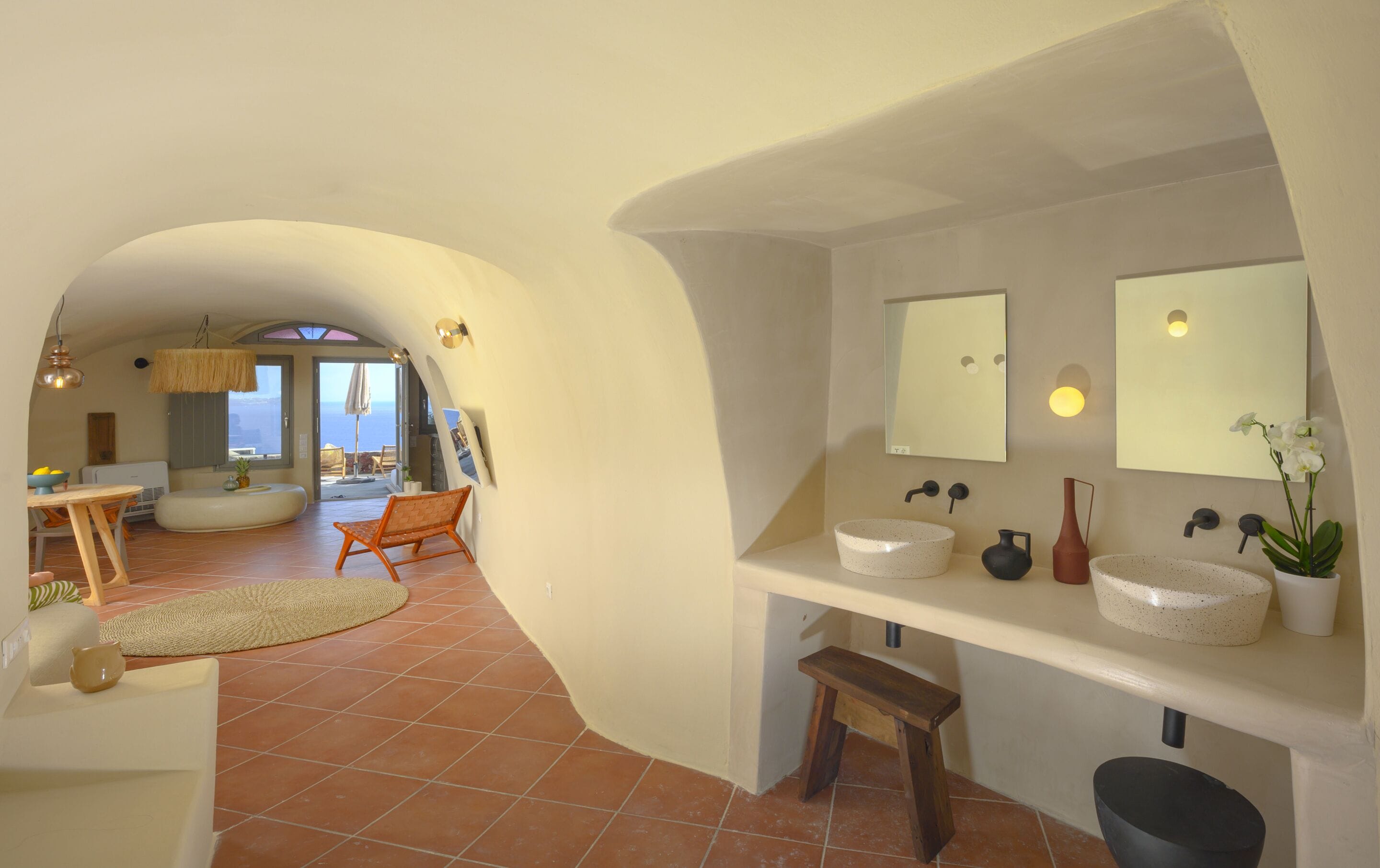 Une salle de bain moderne avec deux grands miroirs, un lavabo et une orchidée en pot.