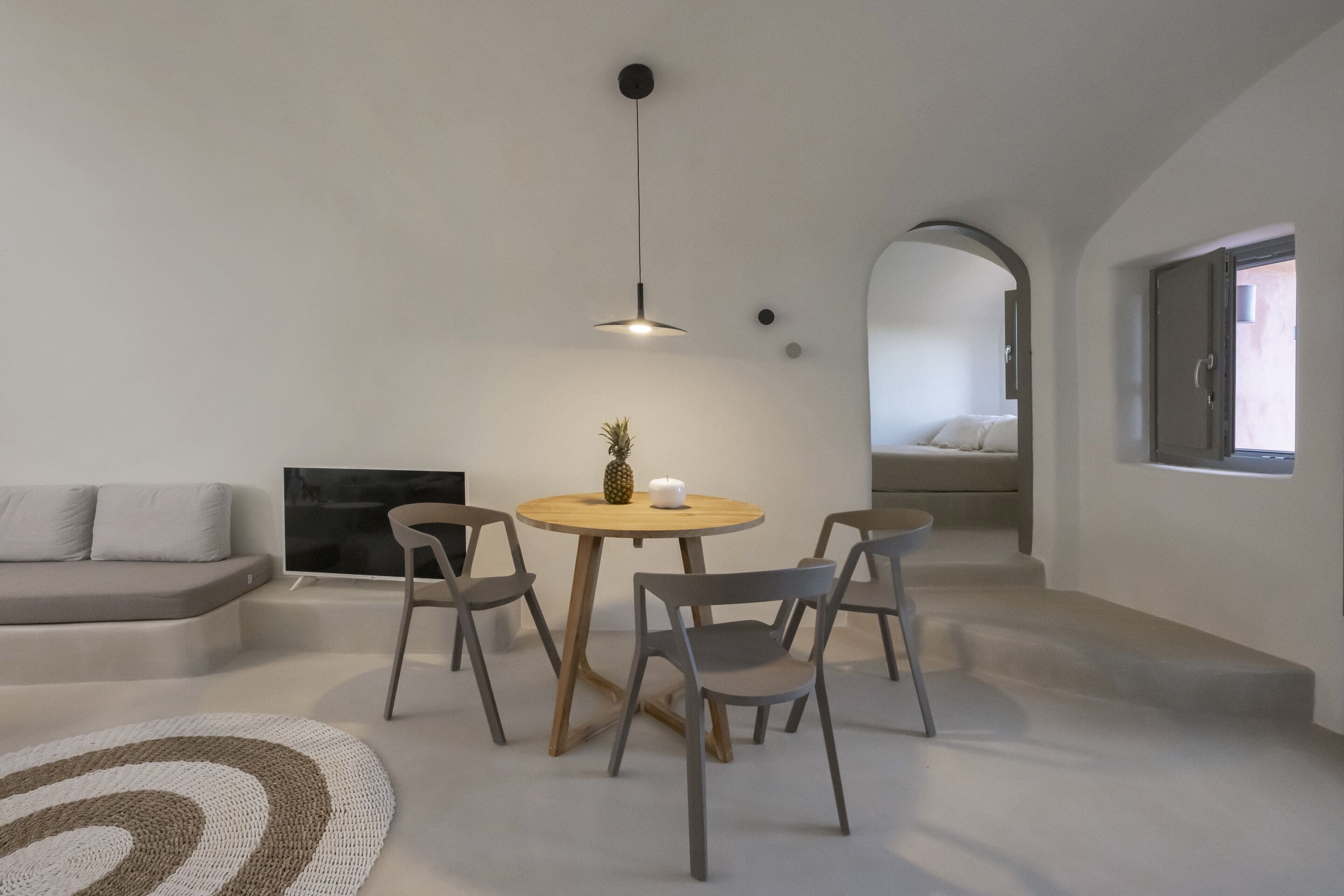 Una sala de estar moderna con una mesa redonda, cuatro sillas, un televisor, una chimenea y un ventanal grande.