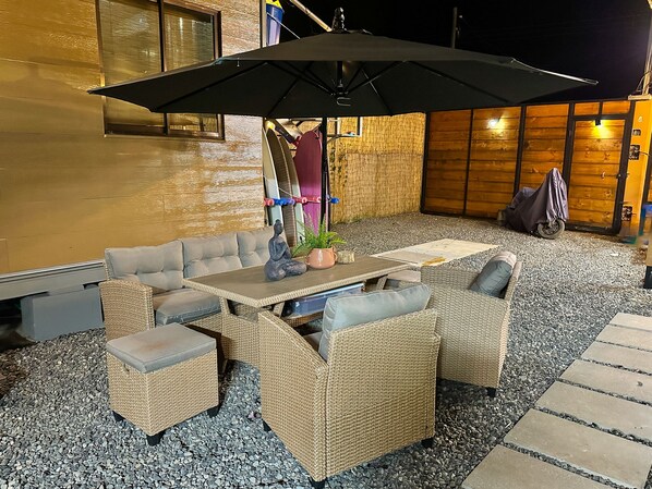 An outdoor seating area with wicker furniture, a table, and an umbrella.