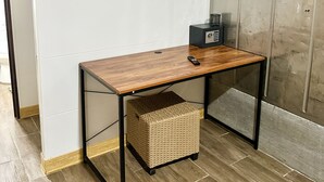 A room with a wooden desk, a television mounted on the wall, and a wicker basket under the desk. - Casa Shaka Jaco with Pool Gym Kitchen  (Jacó)