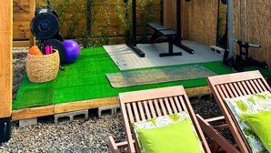 A covered outdoor gym area with a wooden structure, exercise equipment, and green artificial turf. - Casa Shaka Jaco with Pool Gym Kitchen  (Jacó)