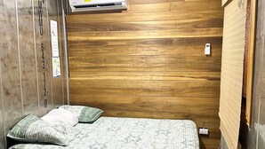 A room with a bed, wooden walls, an air conditioning unit, and a small table. - Casa Shaka Jaco with Pool Gym Kitchen  (Jacó)