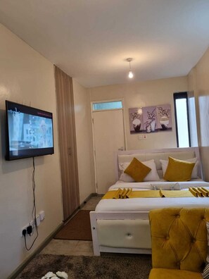 Ein modernes Hotelzimmer mit Bett, Wandfernseher und einem Vorhangfenster.