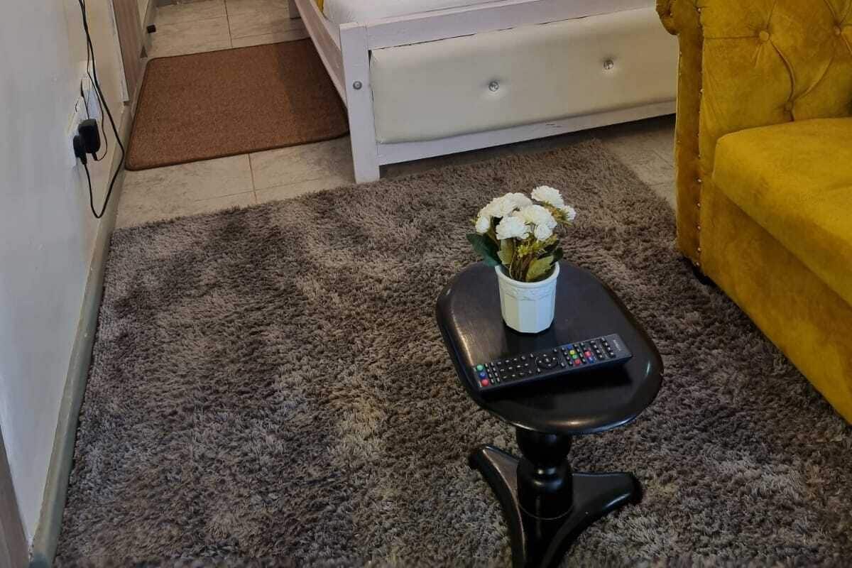 Un dormitorio con una cama, un sofá, una mesita con un jarrón y un cuadro en la pared.