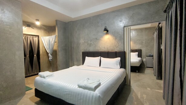 A modern hotel room with a large bed, a headboard, a bedside table, and a mirror. - The Loftel Resort (Bangkok)