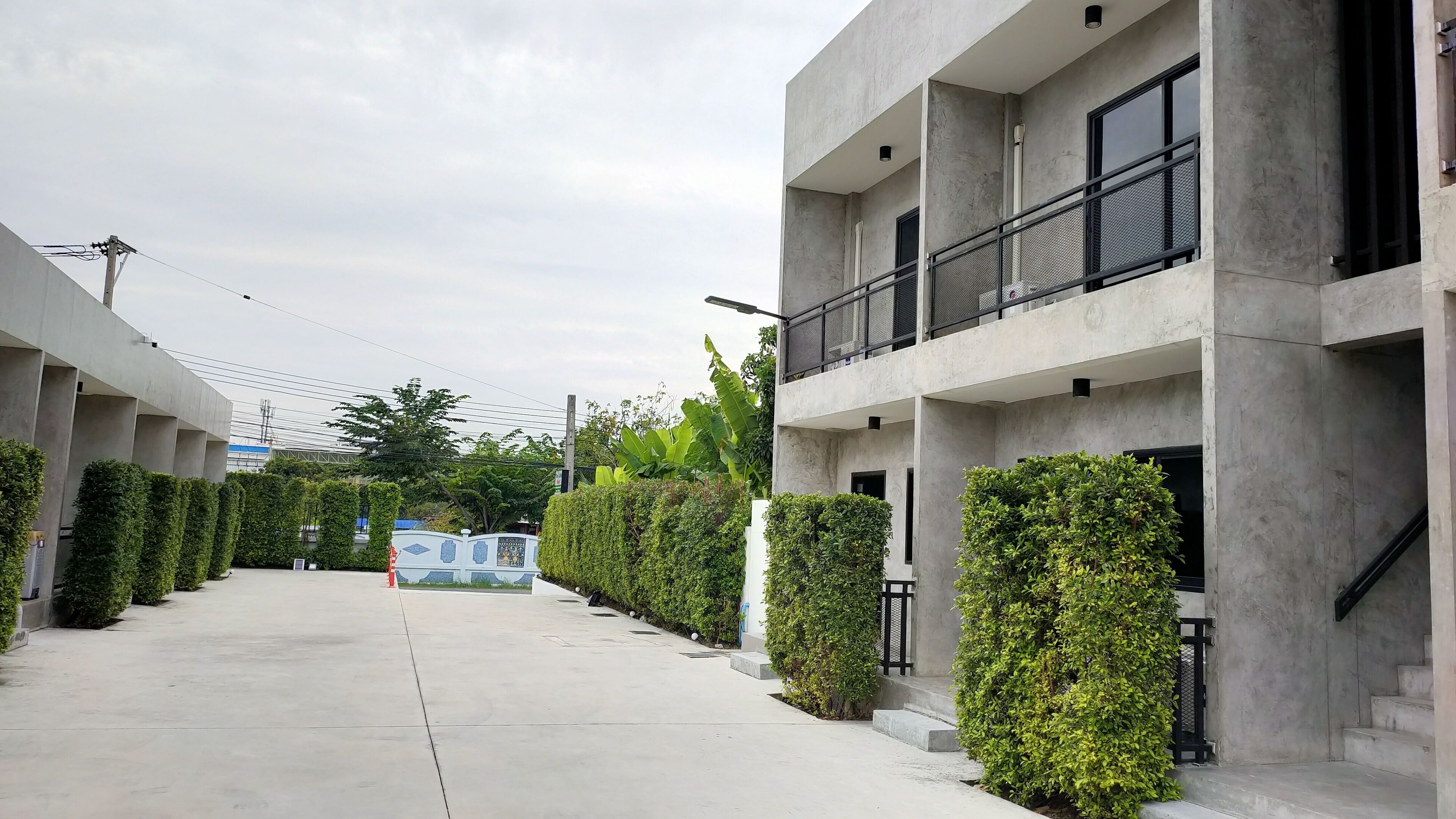 Un edificio moderno con fachada de concreto, un sendero central y setos bien recortados.