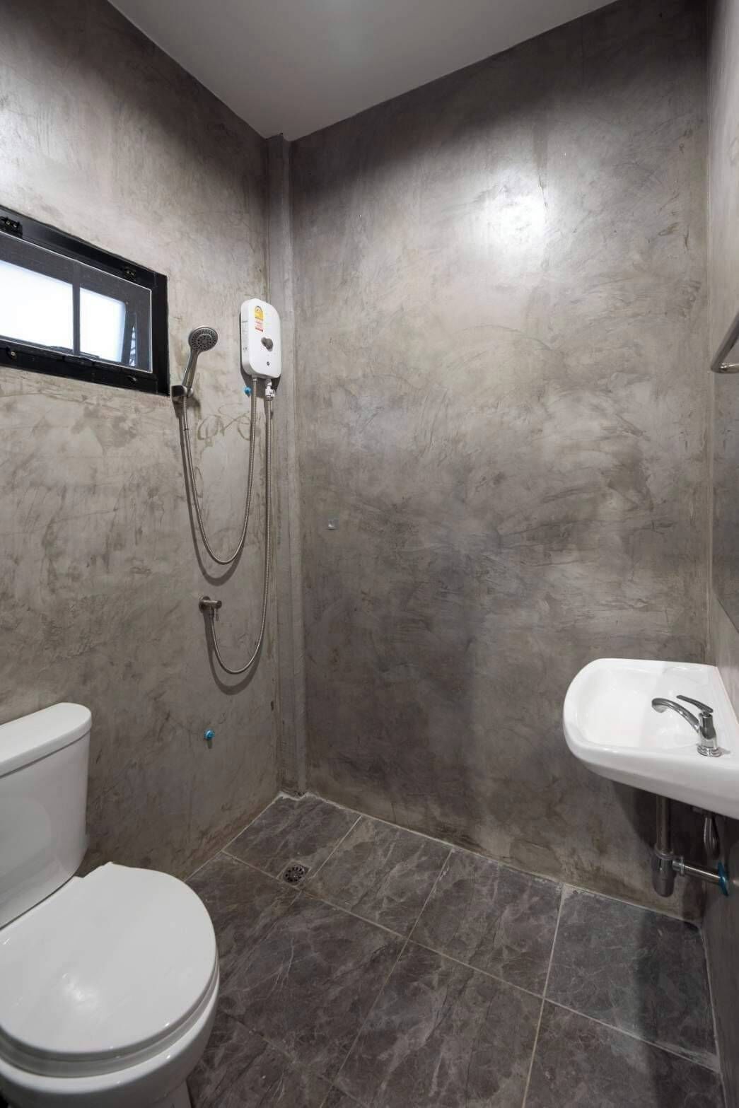 Un bany amb vàter, dutxa amb plat de roba i un lavabo.