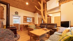 A cozy living room with a fireplace, wooden furniture, and a television. - Yubari City Deer Valley Residence (Yubari)