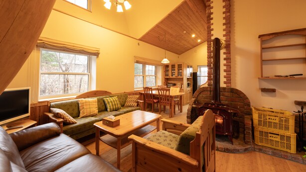 A cozy living room with a fireplace, wooden furniture, and a television. - Yubari City Deer Valley Residence (Yubari)