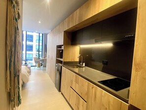 A modern kitchen with wooden cabinetry, a stainless steel range hood, and a built-in oven. - Chic Downtown Loft - Near Zona Rosa (Bogotá)