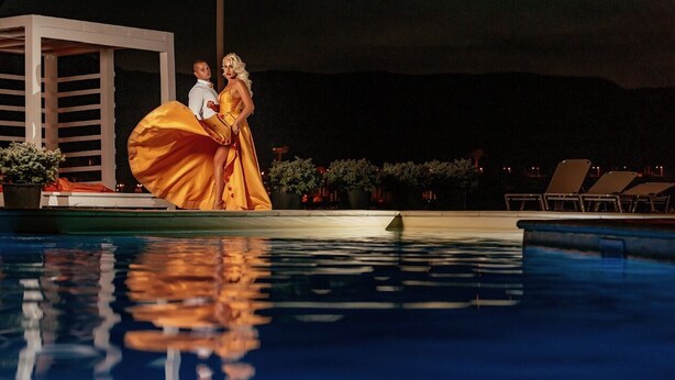 A couple by a pool with a white structure and lounge chairs in the background. - Riviera by Queens (Drobeta-Turnu Severin)