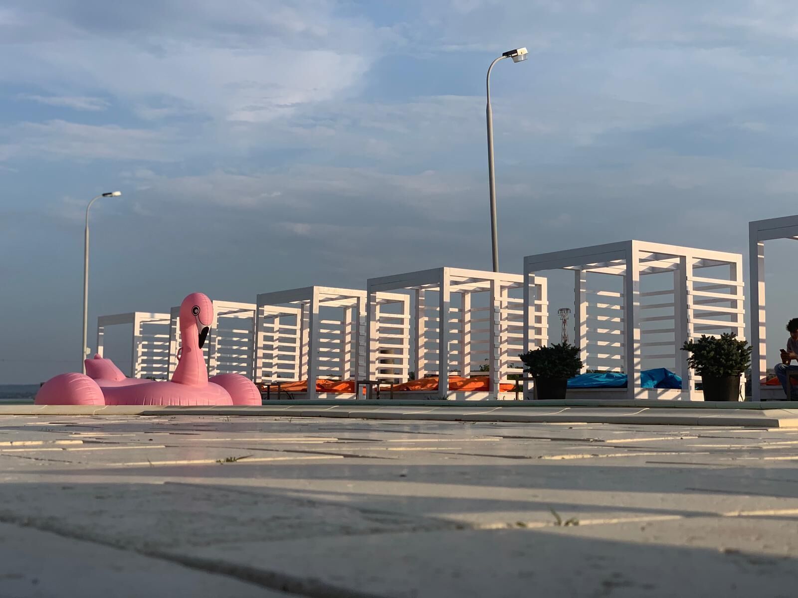 Una playa con estructuras blancas, un flamenco inflable rosa y faroles.