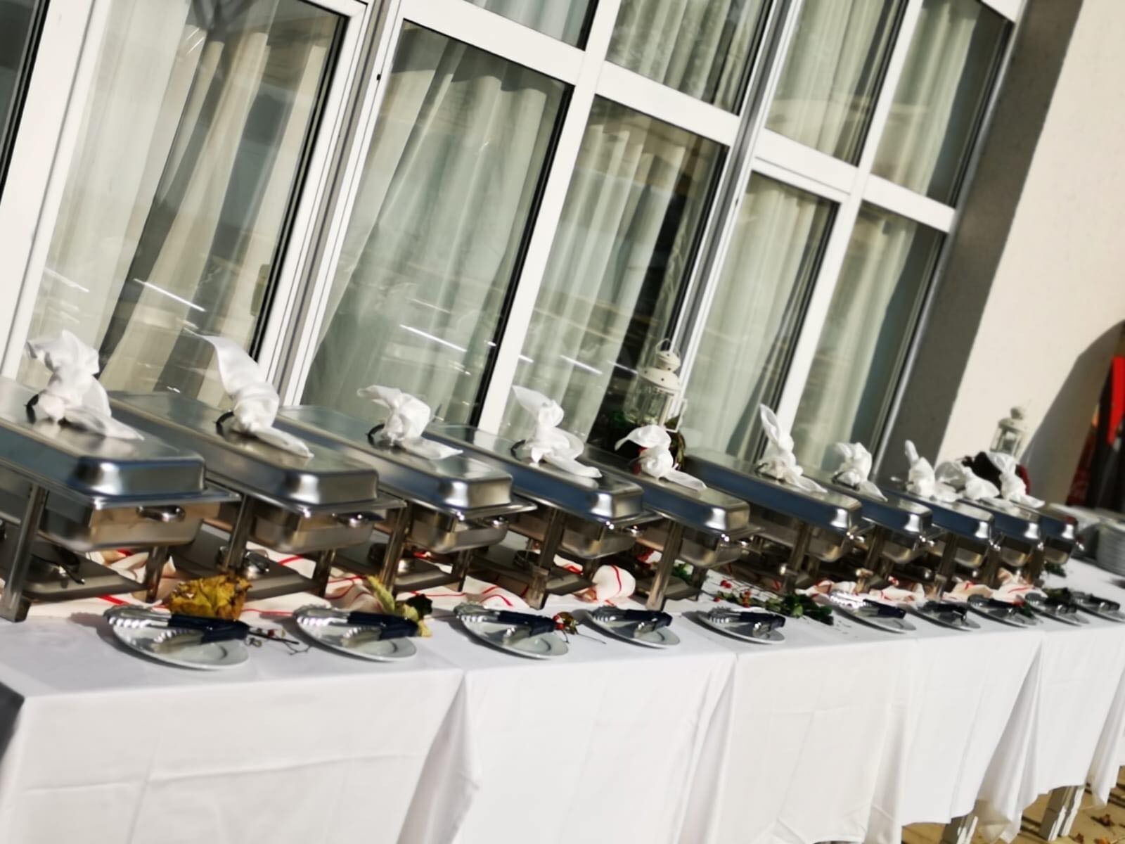 A buffet setup with multiple serving stations, each with a tray and utensils.