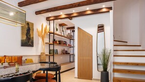 A modern interior with a wooden staircase, a bookshelf, and a dining area with a glass table. - Modern Stone Villa Lemonia w/(heated-hot tub)pool/Steam room, Old City, Rethymno (Rethymno)