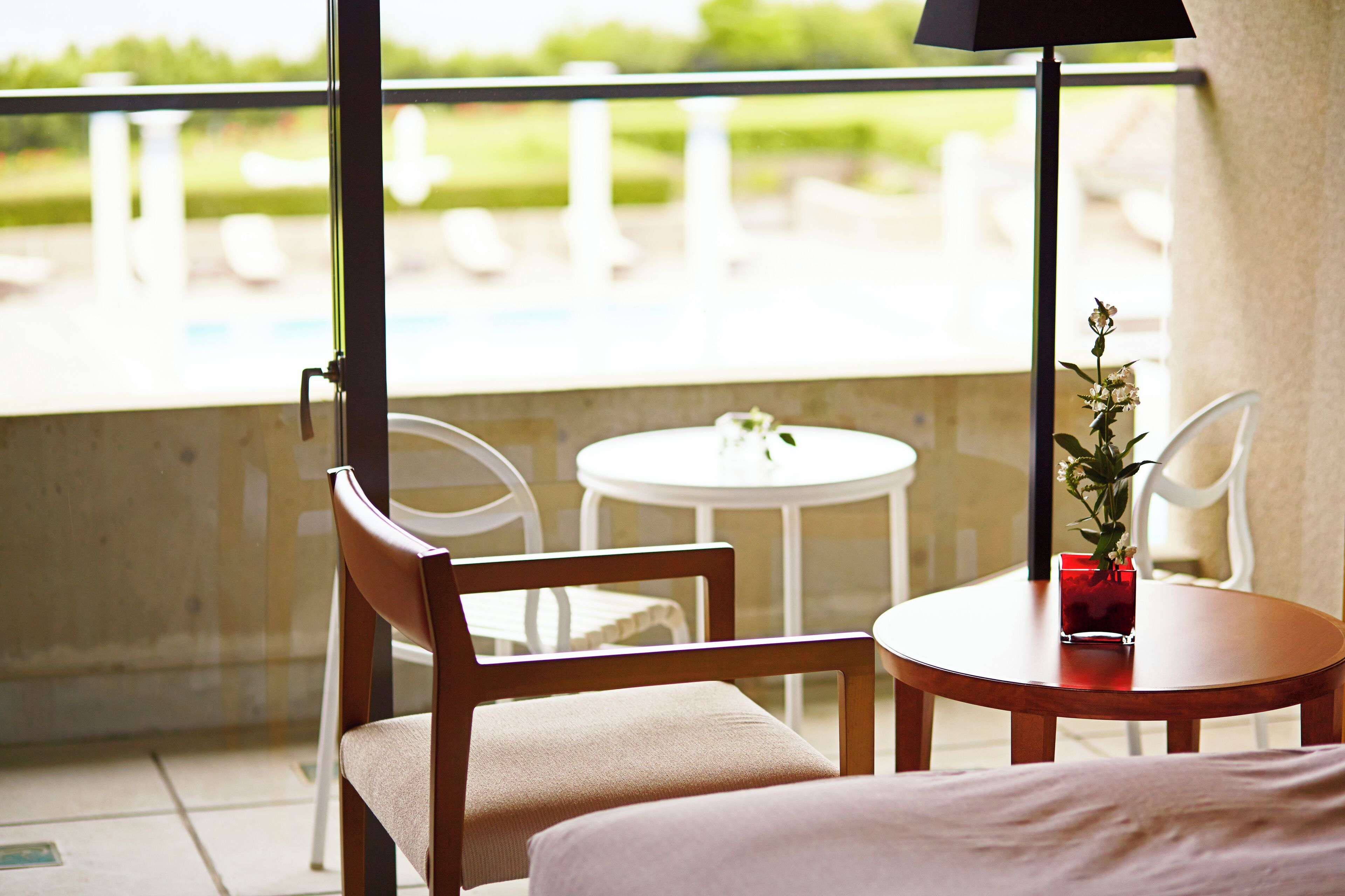 Un balcon avec une chaise en bois, une petite table ronde et un pot de fleurs.