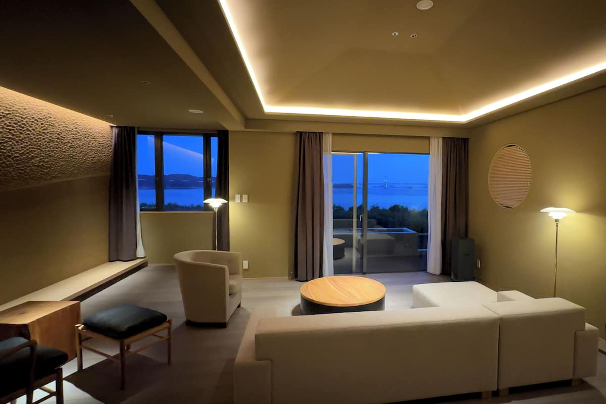 Ett modernt hotellrum med en soffa, ett runt bord och utsikt över omgivningarna.
