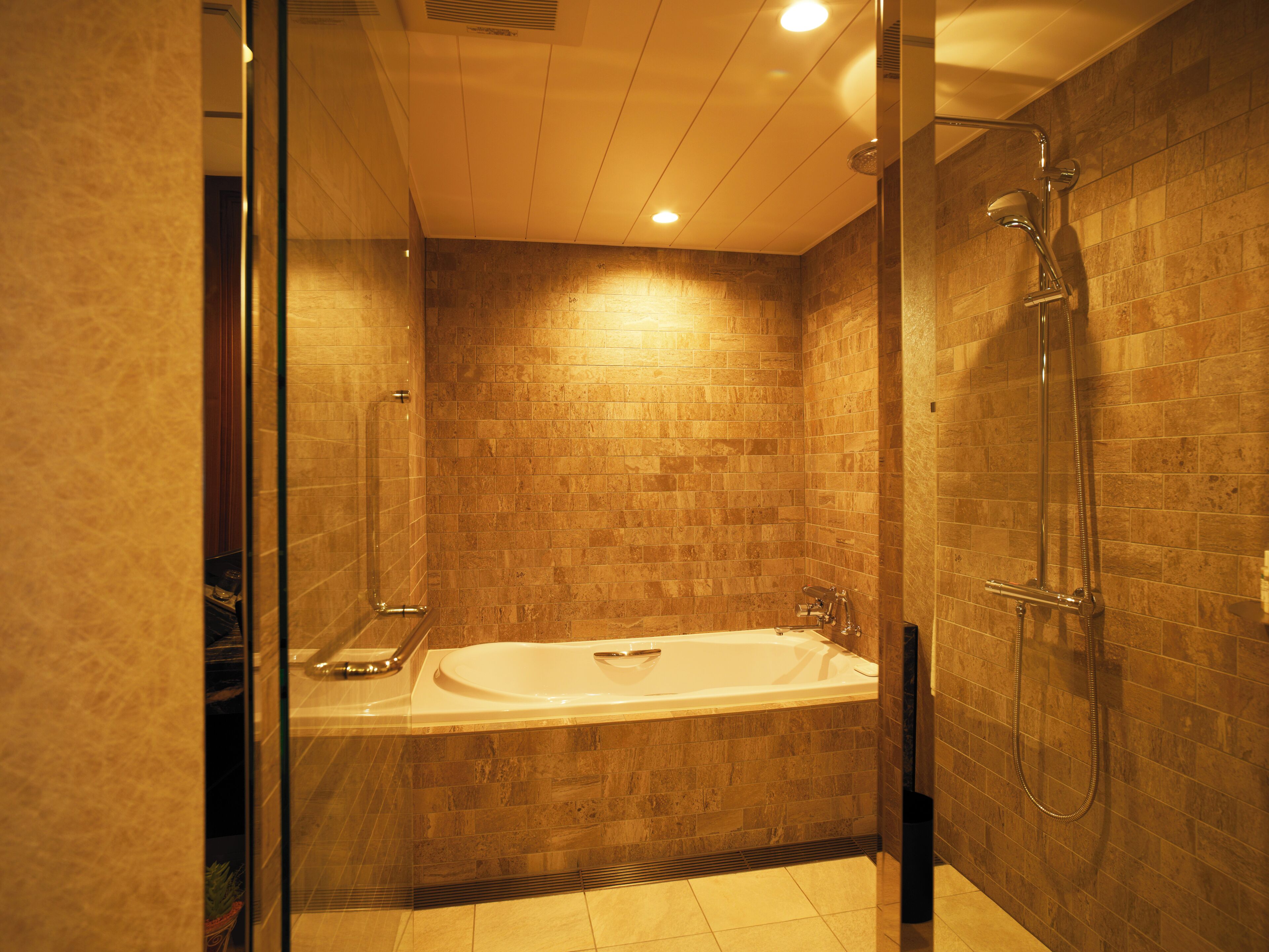 A modern bathroom with a glass-enclosed shower, a freestanding bathtub, and tiled walls.