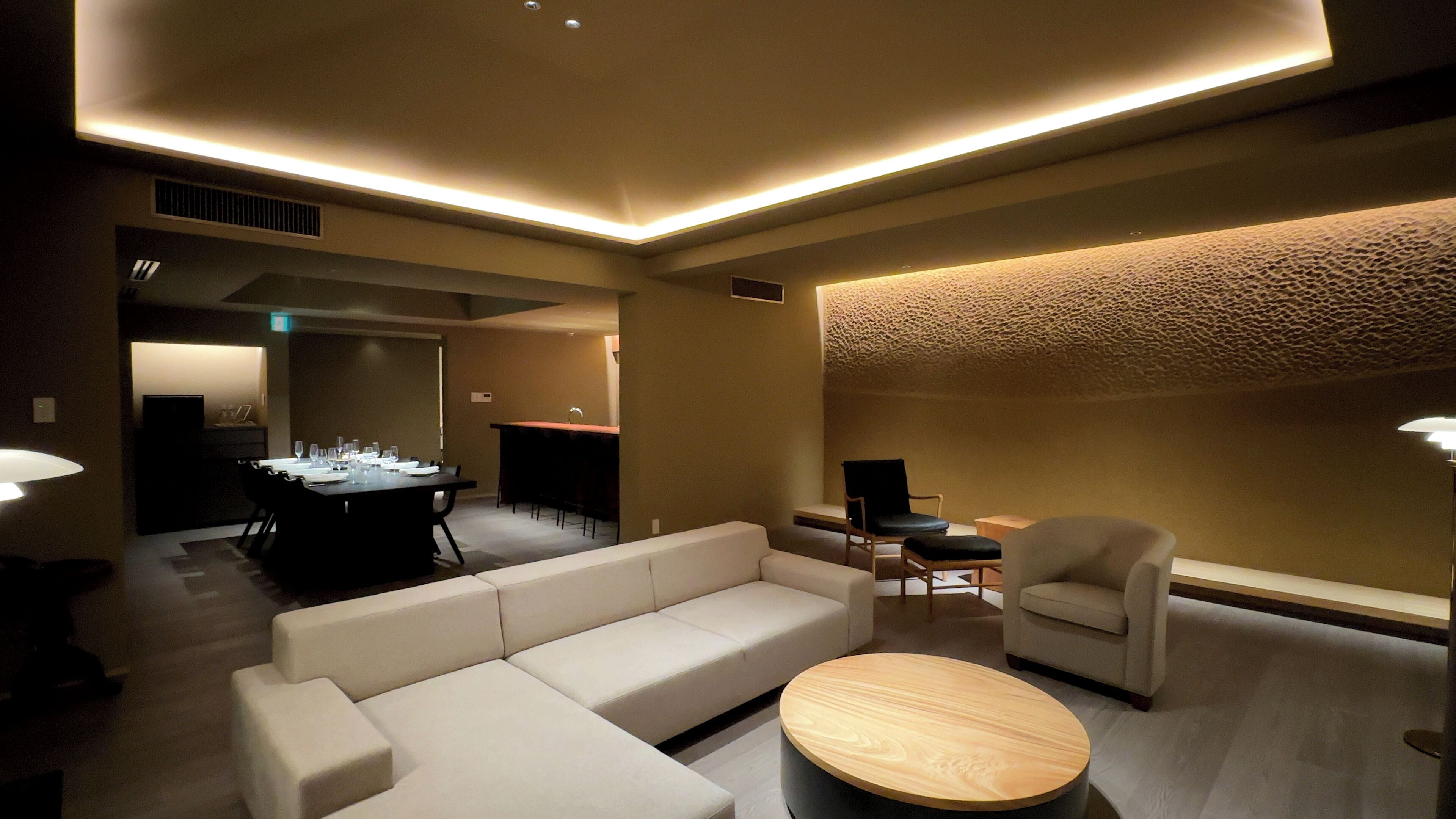 A modern living room with a sectional sofa, a round coffee table, and a dining area with a table set for six.