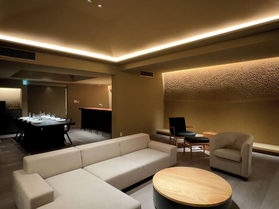 A modern living room with a sectional sofa, a round coffee table, and a dining area with a table set for six.