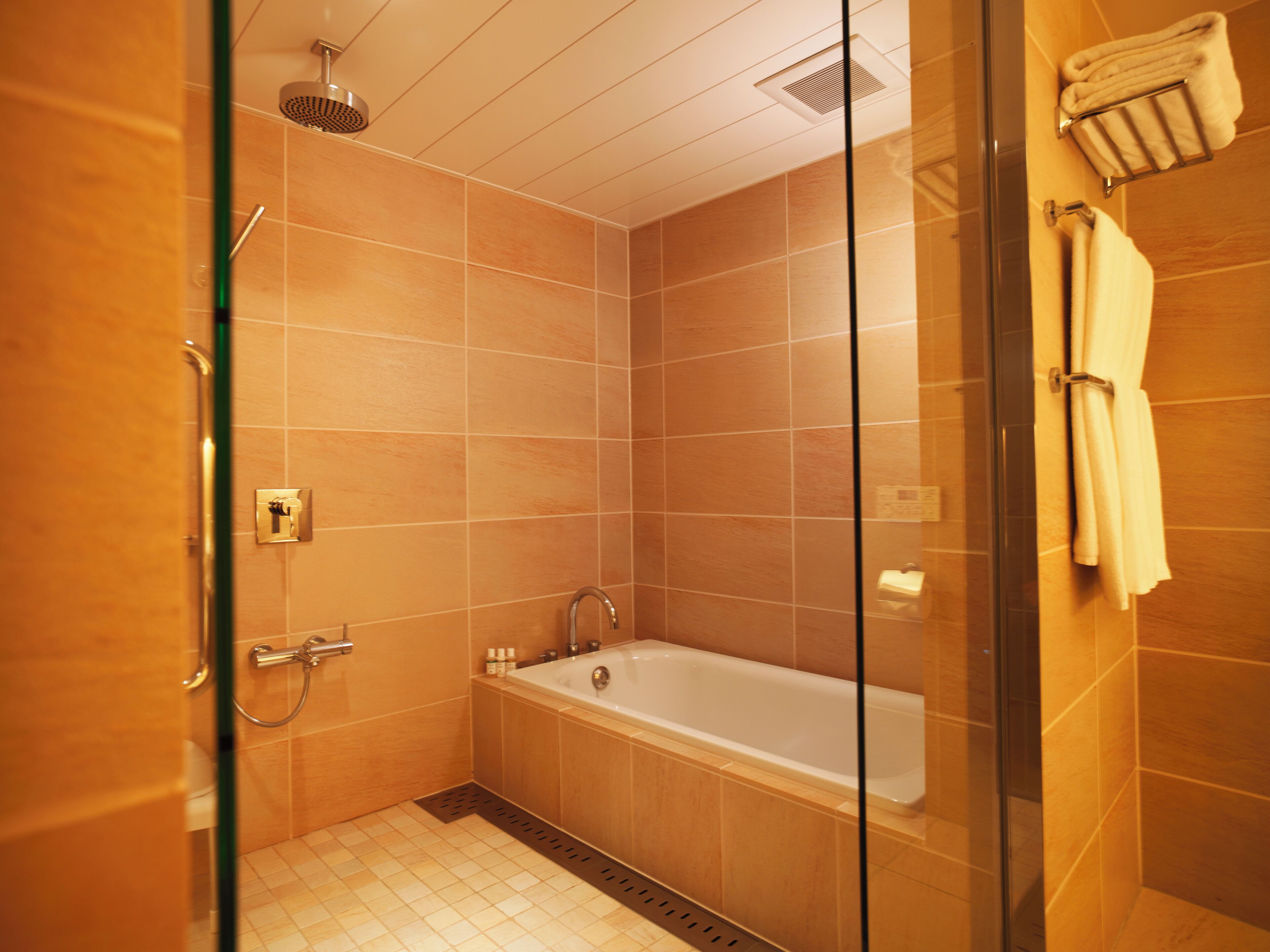 Ein modernes Badezimmer mit einer gläsernen Duschkabine, einer freistehenden Badewanne und einem Handtuchhalter.