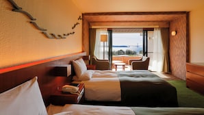 A hotel room with two beds, a desk with a phone, a chair, a small table, and a view of the outdoors. - Hotel Anaga (Minamiawaji)