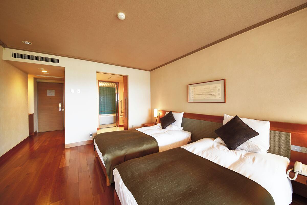 Ett hotellrum med två sängar, ett inramat certifikat på väggen och en telefon på nattduksbordet.