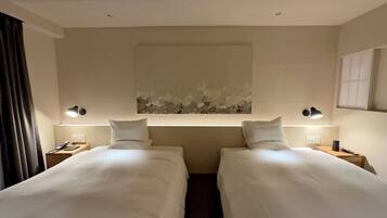 Une chambre d’hôtel avec deux lits simples, une grande peinture abstraite au mur et des lampes de chevet.