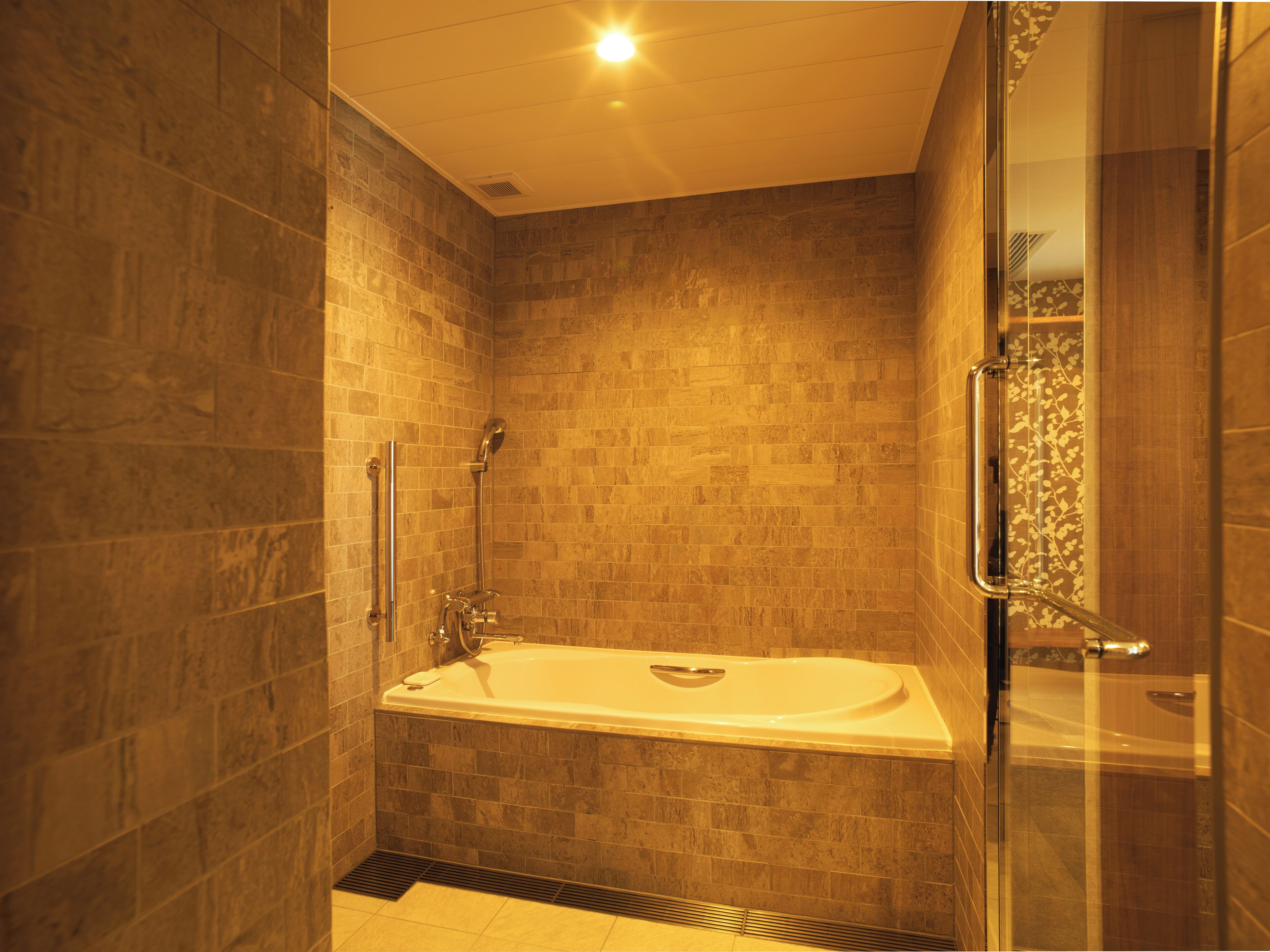 Une salle de bain moderne dotée d’une douche à parois de verre, d’une baignoire à porte et de murs carrelés.