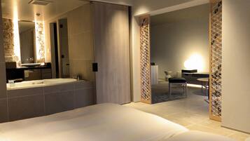 Une chambre d’hôtel moderne dotée d’un grand lit, d’une salle de bain avec baignoire et d’un coin repas avec une table et des chaises.