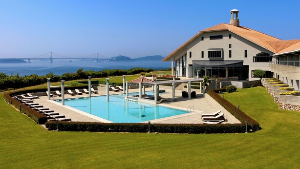 A modern house with a swimming pool, a view of a bridge, and a well-maintained lawn. - Hotel Anaga (Minamiawaji)