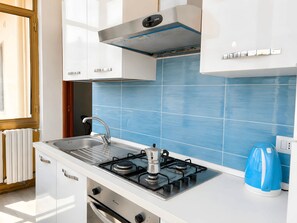 A modern kitchen with white cabinets, a gas stove, a sink, and blue tiles. - From Sorrento With Love - Big sea view apartment in center of Sorrento (Sorrento)