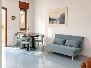 A room with a dining table, chairs, a sofa, a framed picture, and a window. - From Sorrento With Love - Big sea view apartment in center of Sorrento (Sorrento)