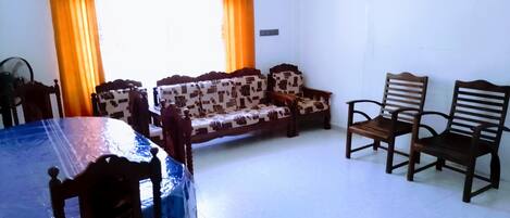 A room with a dining table, a sofa, and two wooden chairs.