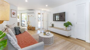 Ein modernes Wohnzimmer mit Sofa, Couchtisch und Fernseher.