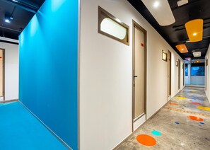 A hallway with doors, a blue wall, and a colorful floor. - L MINITEL (Chiang Mai)