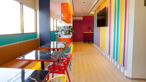 Una cocina moderna con una isla central, un comedor con mesa de vidrio y sillas coloridas, y una pared vibrante a rayas.