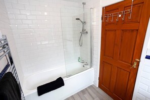 Huis | Badkamer | Een bad/douchecombinatie, een diep bad, een haardroger, handdoeken