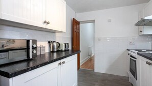 Una cucina moderna con mobili bianchi, un piano di lavoro nero ed elettrodomestici in acciaio inossidabile.