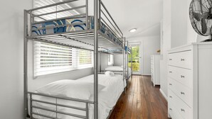 A bunk room with metal bunk beds, a white dresser, and a fan.
