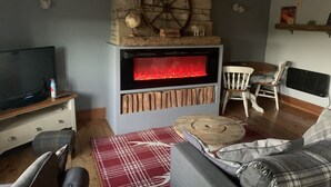 Una sala de estar acogedora con chimenea de piedra, televisor y un área de descanso confortable.