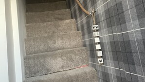Una escalera con un muro a cuadros, un letrero rojo y una placa.